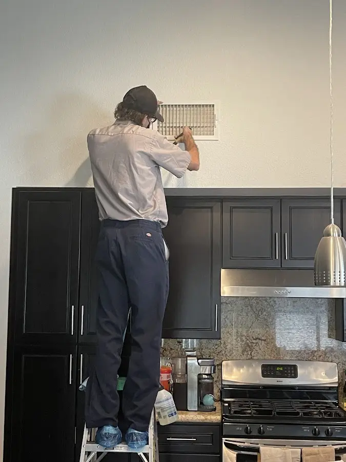 Technician inspecting an air vent during HVAC service in Maltby